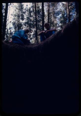Two people looking down into a pit in the ground