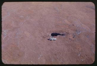 Aerial shot of hole in ground with white vehicle