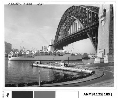 P&O liner ARCADIA passing under the Sydney Harbour Bridge, with the stern of what is possibly the liner IBERIA seen moored in Sydney Cove