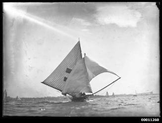 18-foot skiff HC PRESS sailing on Sydney Harbour with south pylon of Sydney Harbour Bridge under early construction on skyline at right
