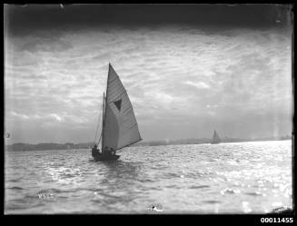 18-foot skiff with inverted triangle sail insignia heads across Sydney Harbour