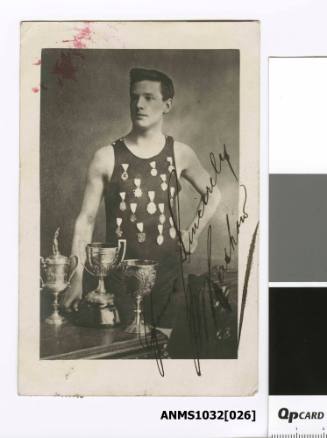 A man in a swimming costume, with several badges pinned to his chest