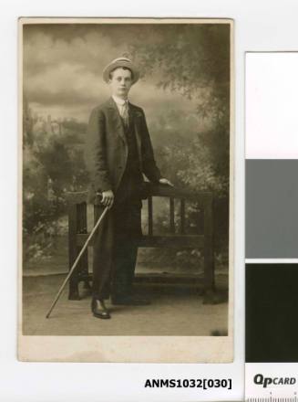 A man wearing a suit and a hat, and holding a walking cane