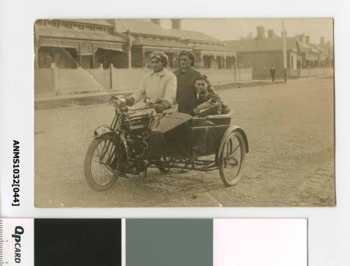 Photographic postcard of three men and a dog in a motorcycle and sidecar