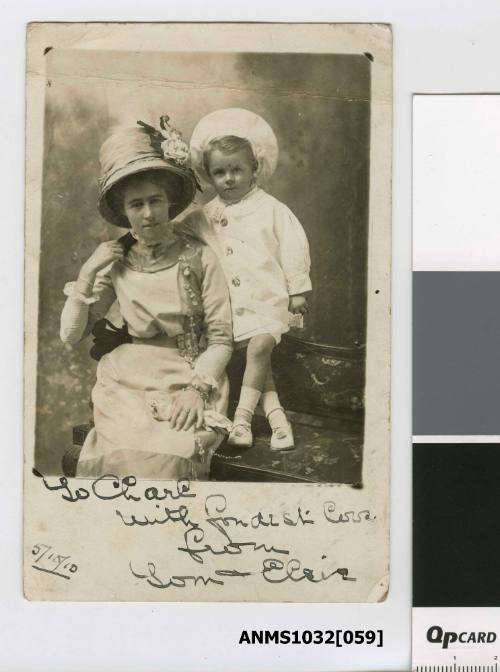 A woman sitting on a chair, with her young son standing on the chair beside her