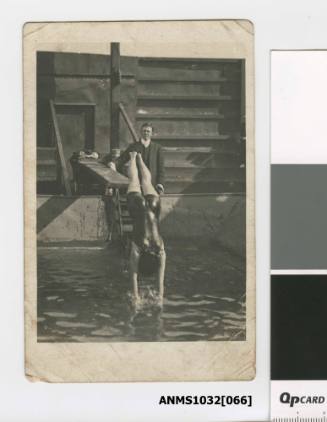 A woman diving into the water, presumably Beatrice Kerr, with a man in a suit standing behind her next to the diving board