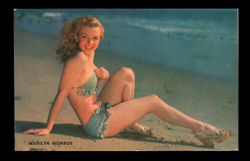 Vintage postcard of Marilyn Monroe modelling a striped bikini on a beach