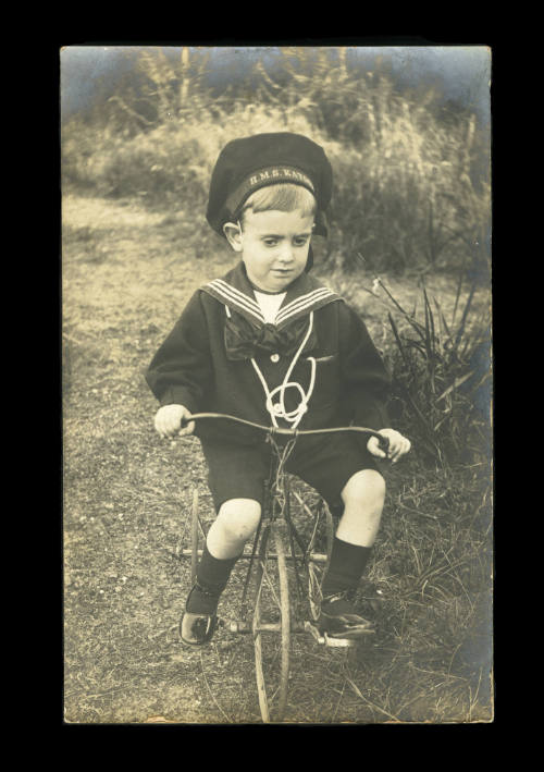 Little Jack Danahay in sailor outfit riding a tricycle