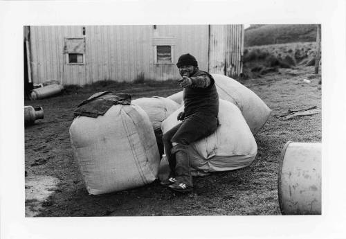 Untitled (Kerry Maynard sitting on sacks of feathers)