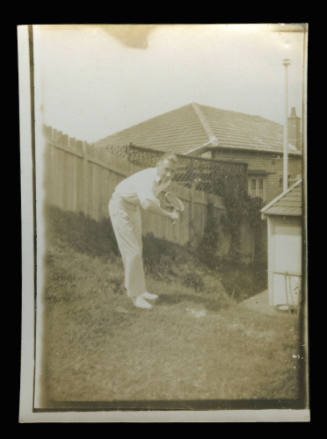 Man standing on grass in backyard holding a racket