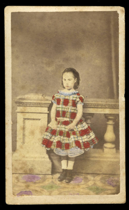 Young girl standing in front of a balustrade, wearing a dress