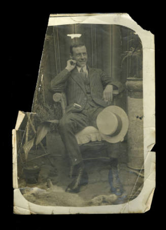 Man, possibly Beatrice Kerr’s husband, reclining in a chair, with his hat resting on his knee, and holding a cigarette in his hand