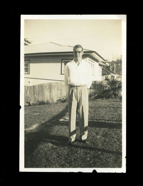 Man standing in a garden with his hands behind his back