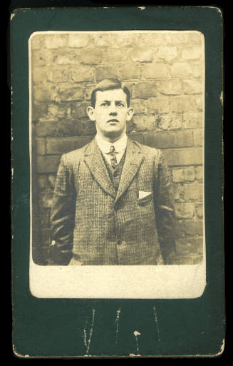 Black and white photograph of B B Keiran leaning against a brick wall