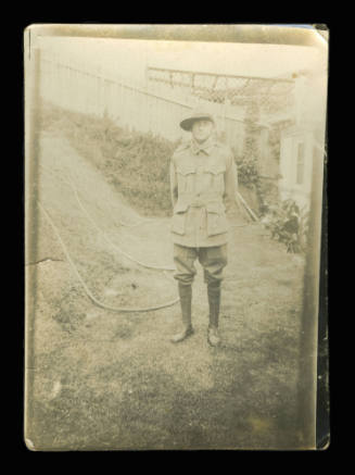 Soldier in full army uniform, standing in the backyard of a house