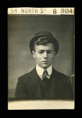 Man wearing a dark coloured waistcoat and jacket, and dark coloured top hat