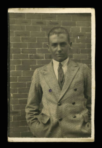Man, possibly G L Williams, with his hands in his suit jacket pockets, staring at the camera