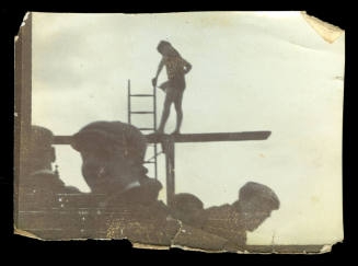 Woman holding onto a ladder, and standing on a diving board, presumably Beatrice Kerr