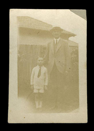 Man standing with his hand on the shoulder of a young boy, the child probably being the son of Beatrice Kerr