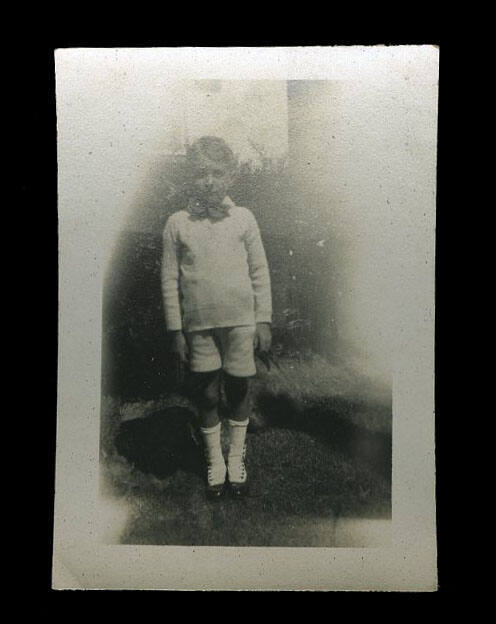 Young boy wearing pale coloured clothing, with a dark coloured bow tie