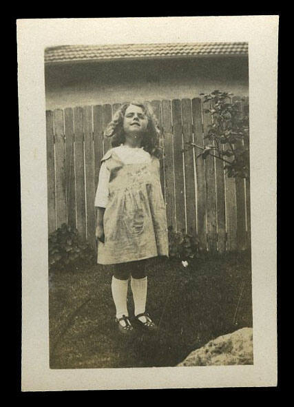 Young girl standing in front of a wooden fence