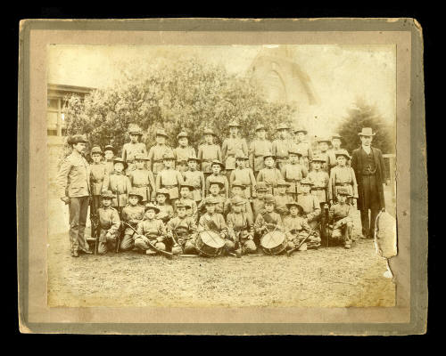 A group of young boys in uniform, with men standing either side of the group