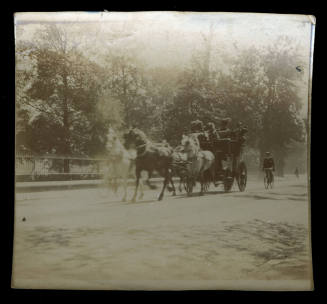 Black and white photograph of four horses pulling a carriage with four people sitting in the carriage