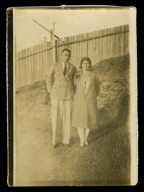 Black and white photograph of Beatrice Kerr and possibly her son, standing next to each other in a garden with a wooden fence in the background