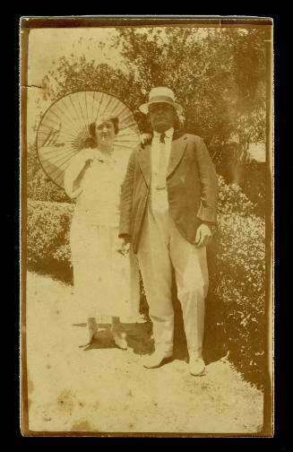 Man and a woman standing beside a hedge in a garden