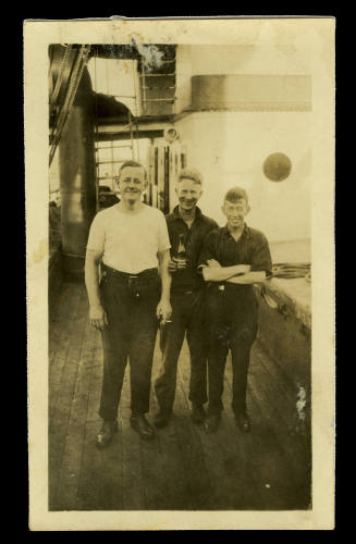 Black and white photograph of three men on a ship’s deck