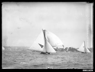 Two 18-foot skiff sail on Sydney Harbour past Point Piper