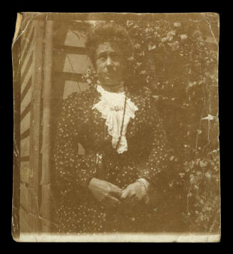 Woman holding her hands, wearing a dark dress with a white lace neckpiece