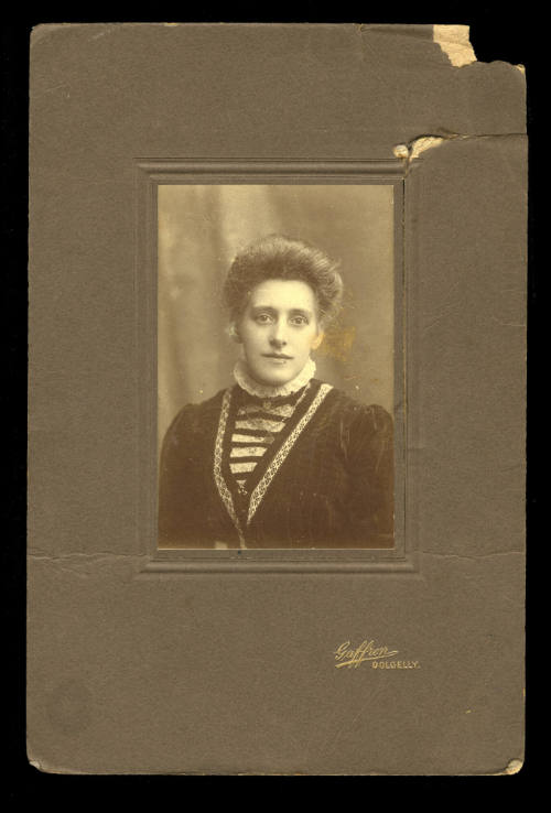 Woman with a dark coloured jacket, white lace colour and black and white striped undershirt