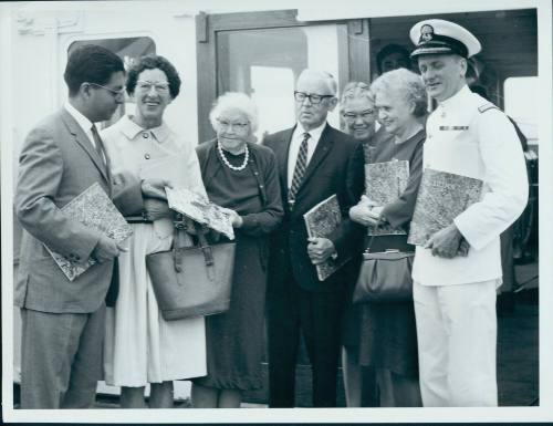 Float and fly to India. Mr B. Singh, assistant trade commissioner, presents travel literature to passengers on SS HIMALAYA