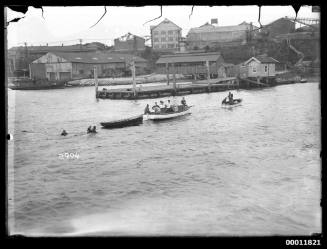 Swamped skiff being towed in off Cockatoo Island wharf, Sydney Harbour