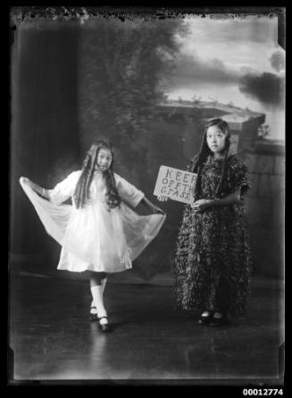 Two Chinese girls in fancy dress, one holding a sign 'Keep off the grass'.  Negative numbered '468'.