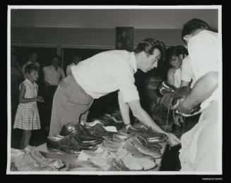 Man assisting group of young men with selection of shoes