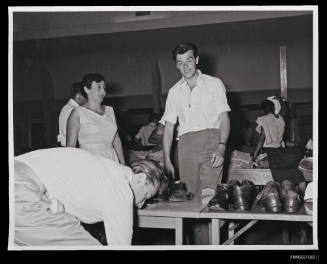 Man and woman assistants watch man trying on shoes