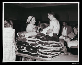 Woman and man talk beside clothing piles