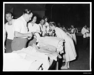 Group of men examine clothing on tables