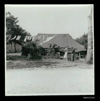 Large canvas tent with man and woman standing outside, possibly a displaced persons camp in Europe