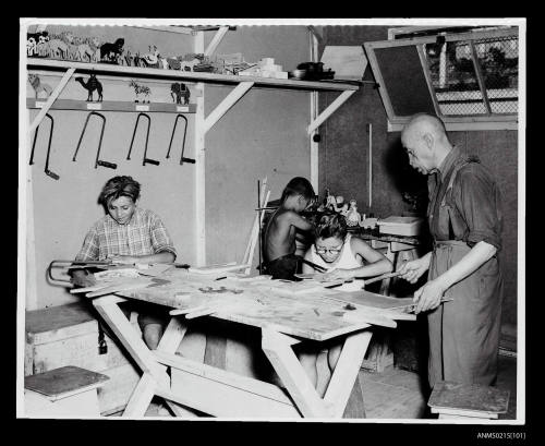 Group of young children playing at a table, displaced persons camp in Europe