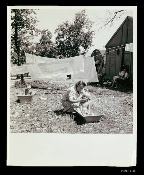 Children in bathtubs in garden at displaced persons camp, Europe