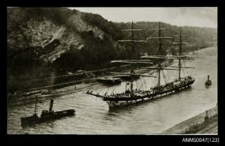 Barque ARETHUSA being towed by two tugs through a canal