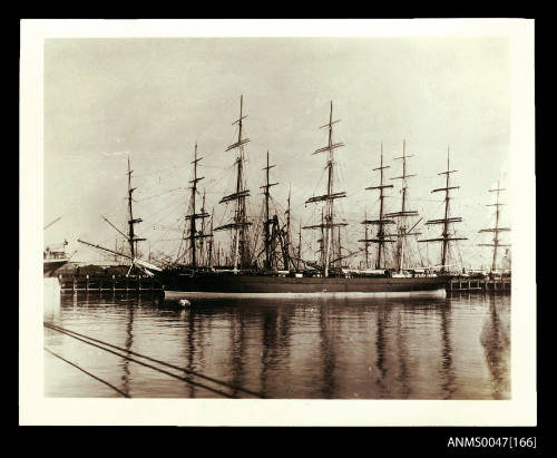 Full-rigged ships crowded in a harbour, coal train in background