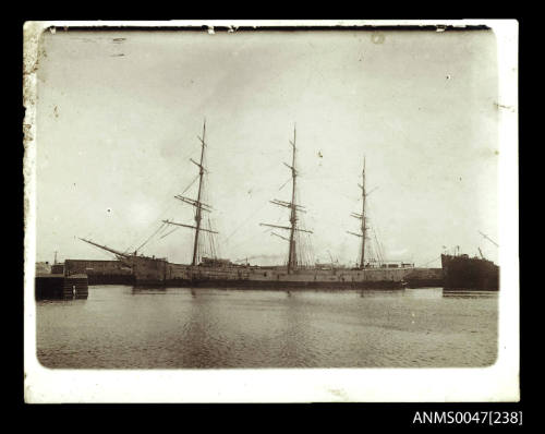 Full-rigged ship docked at a wharf