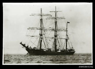 Barque at anchor at sea, crew pose at bow