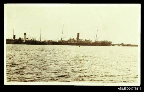 Distant view of the SS ORONTES I docked at a long jetty with other steamships