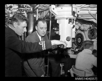 Two men gathered around the periscope of HMS ANCHORITE