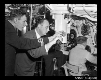 Two men gathered around the periscope of HMS ANCHORITE